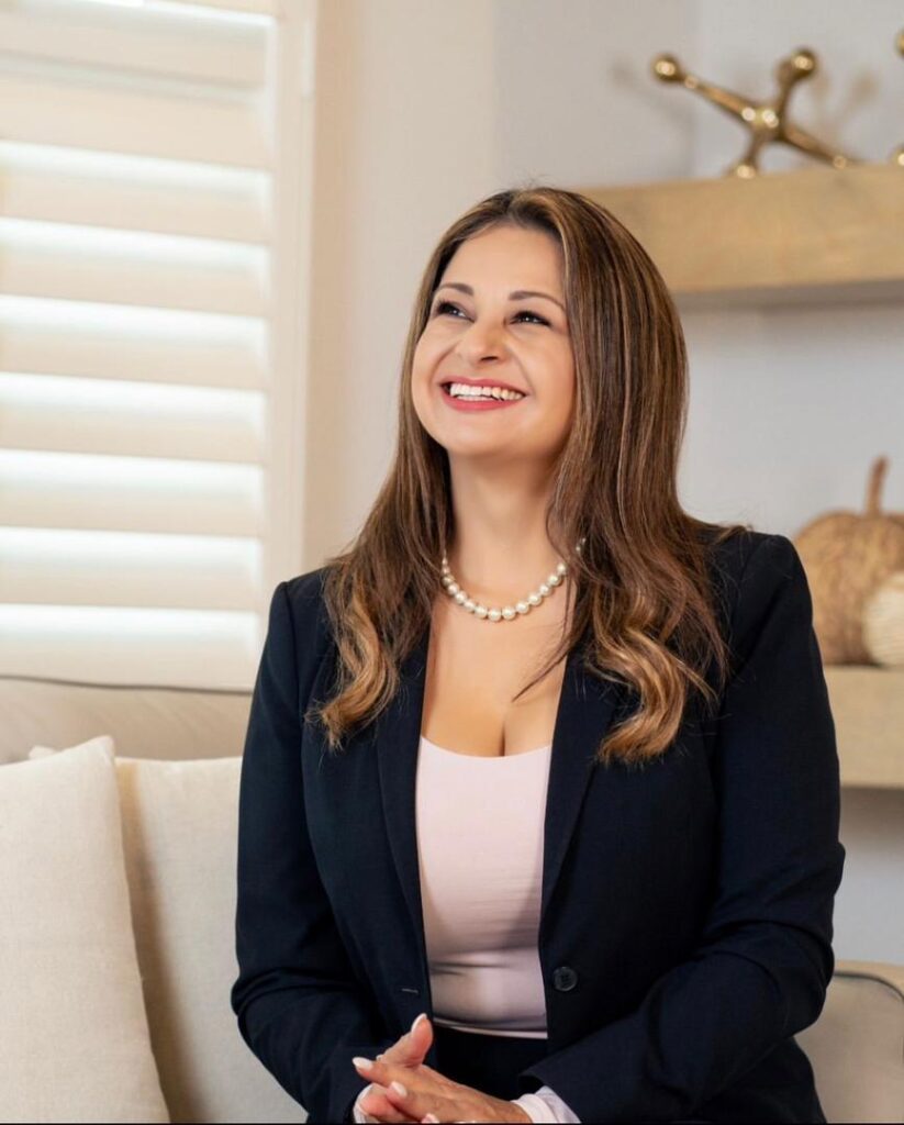 Cynthia McClure Alexander Seated in her living room smiling.